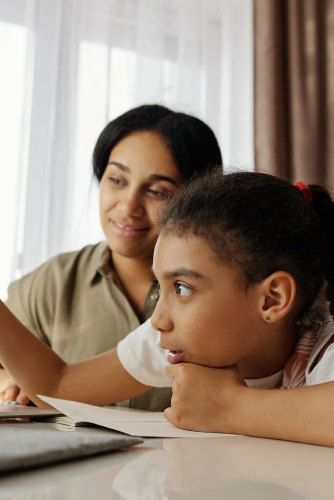 Mother and daughter engaged in online learning at home, using a laptop.