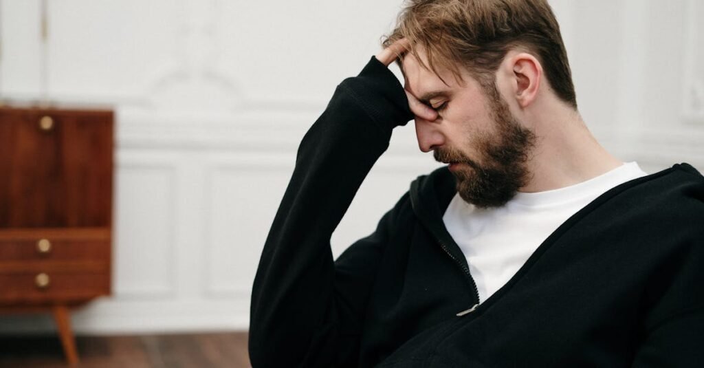 A man sits pensively with his hand on his face, capturing a moment of introspection and stress.